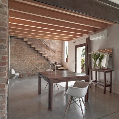 interiors of a dining room overlooks on the entrance with concrete floor, wood ceiling and stairs in a rustic villa