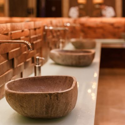 Stylish sink made of light natural stone. Bathroom with stone washbasin on a wooden top in a tropical loft style.